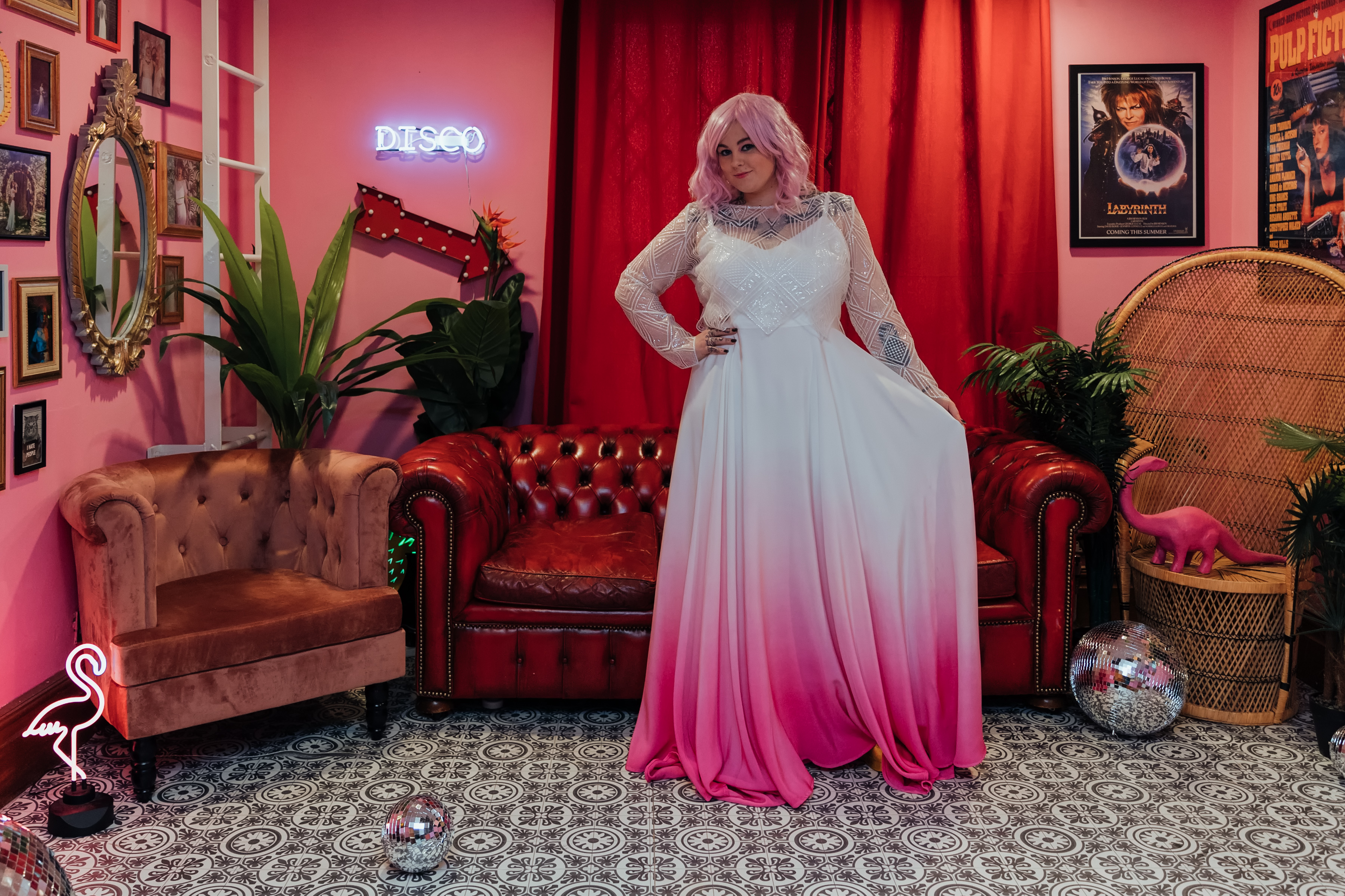 A person wearing a dip-dyed wedding gown with a white top and a gradient from white to pink on the bottom.