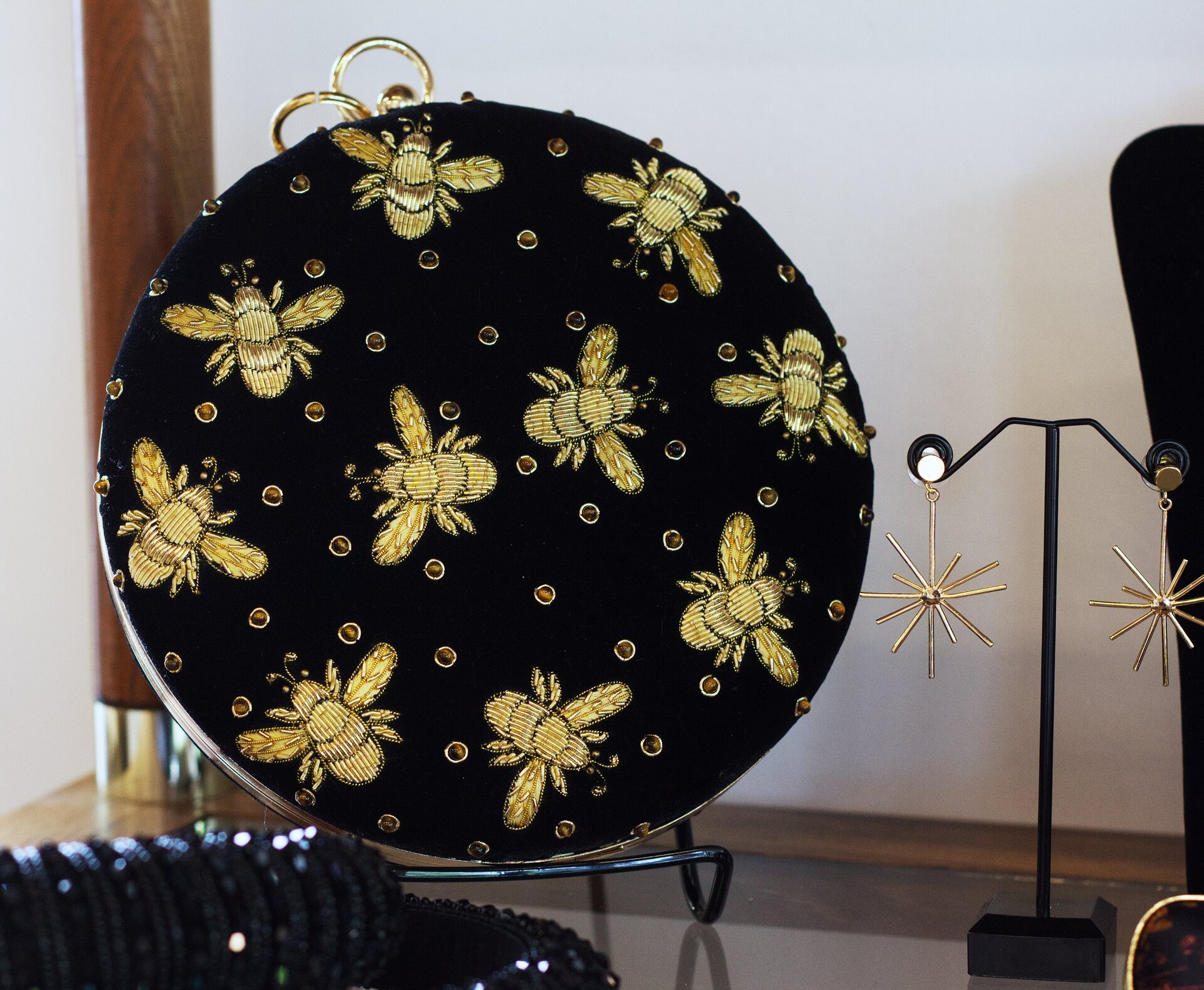 A black handbag with gold beaded bees on it.