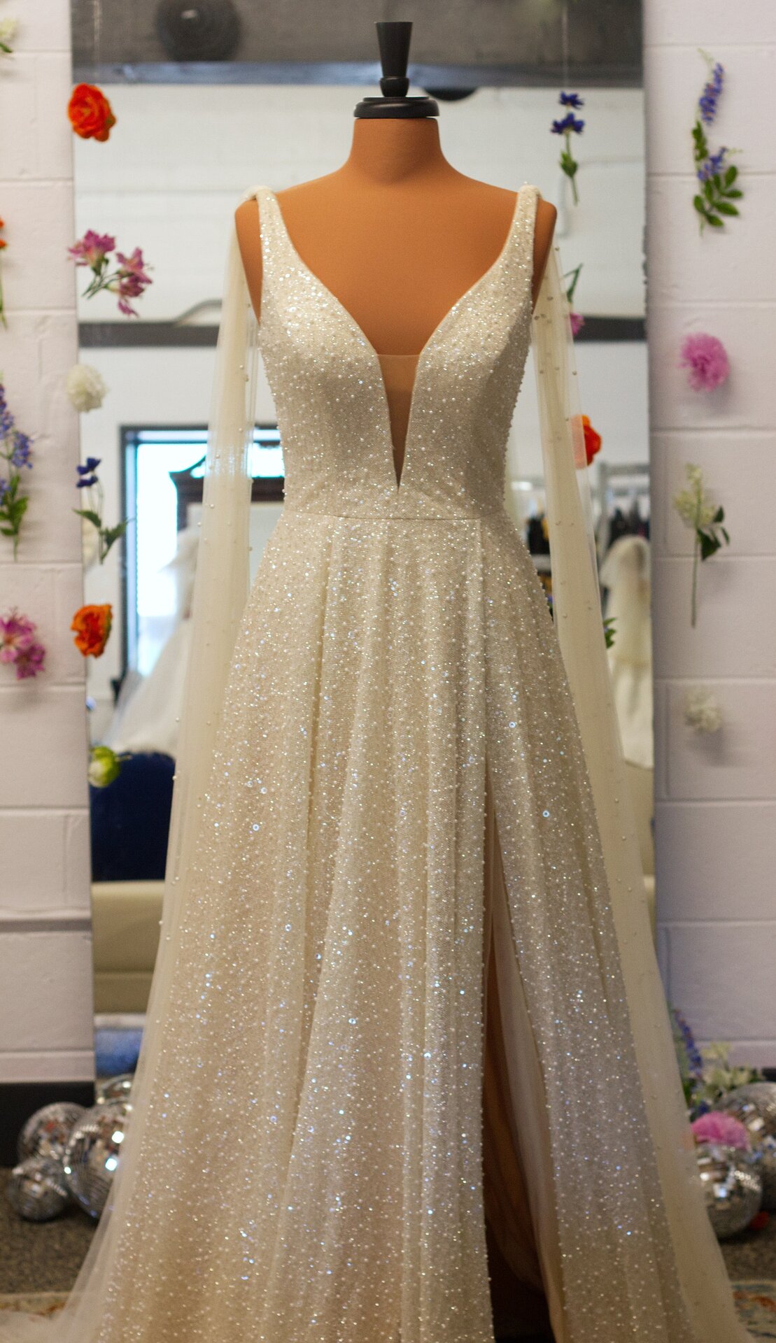 A long A-line champagne wedding dress with sparkly beaded detail and a slit.