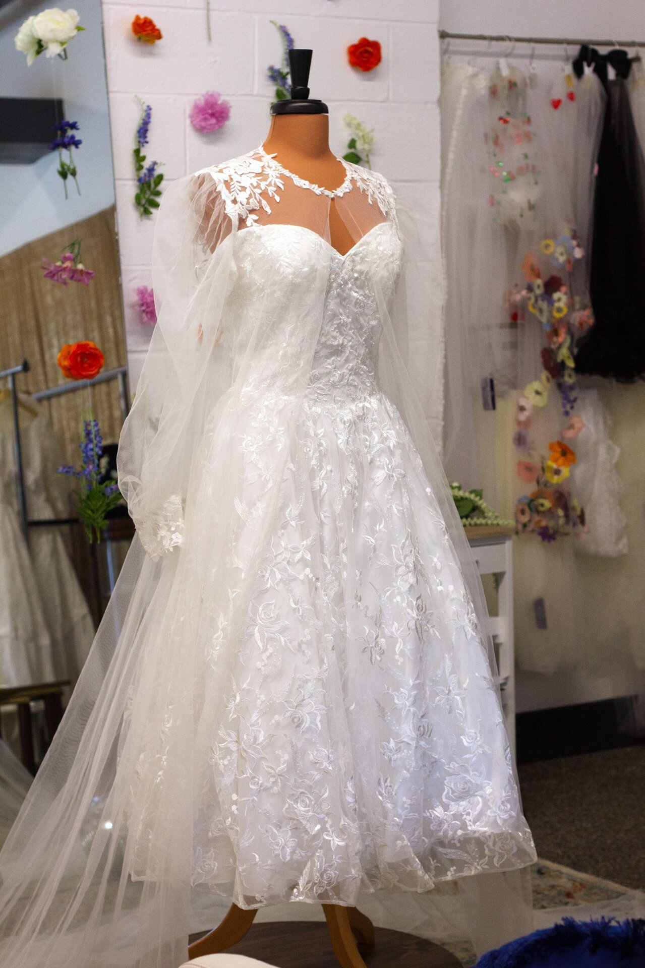 A white tea-length lace dress paired with a bridal cape.