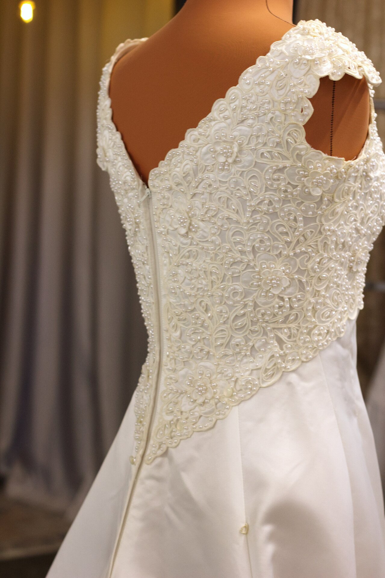A close-up view of beaded details on the back of a vintage wedding dress.