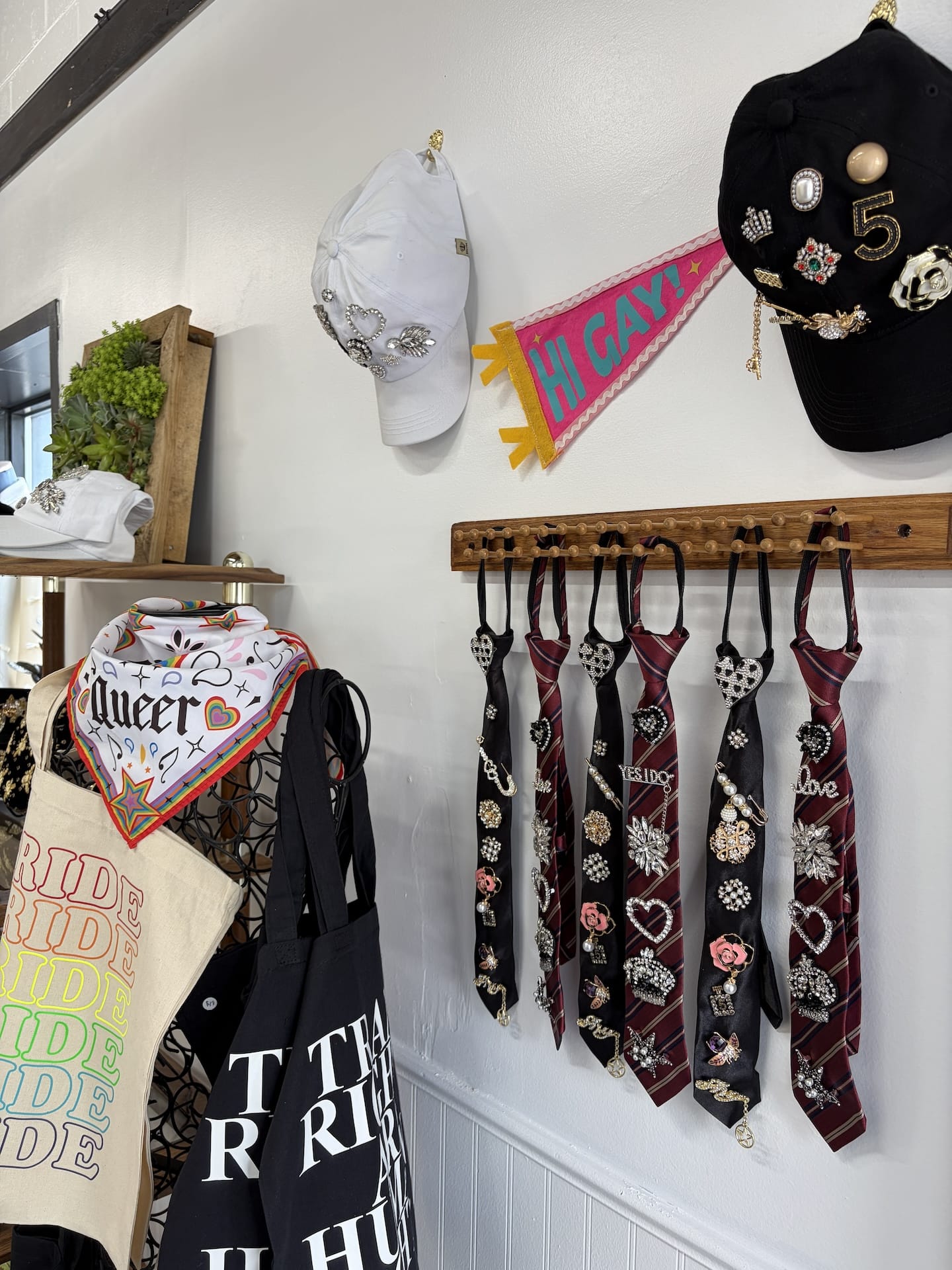 The entrance of the store, showing broached ties on display as well as pride tote bags, bandanas, and hats.